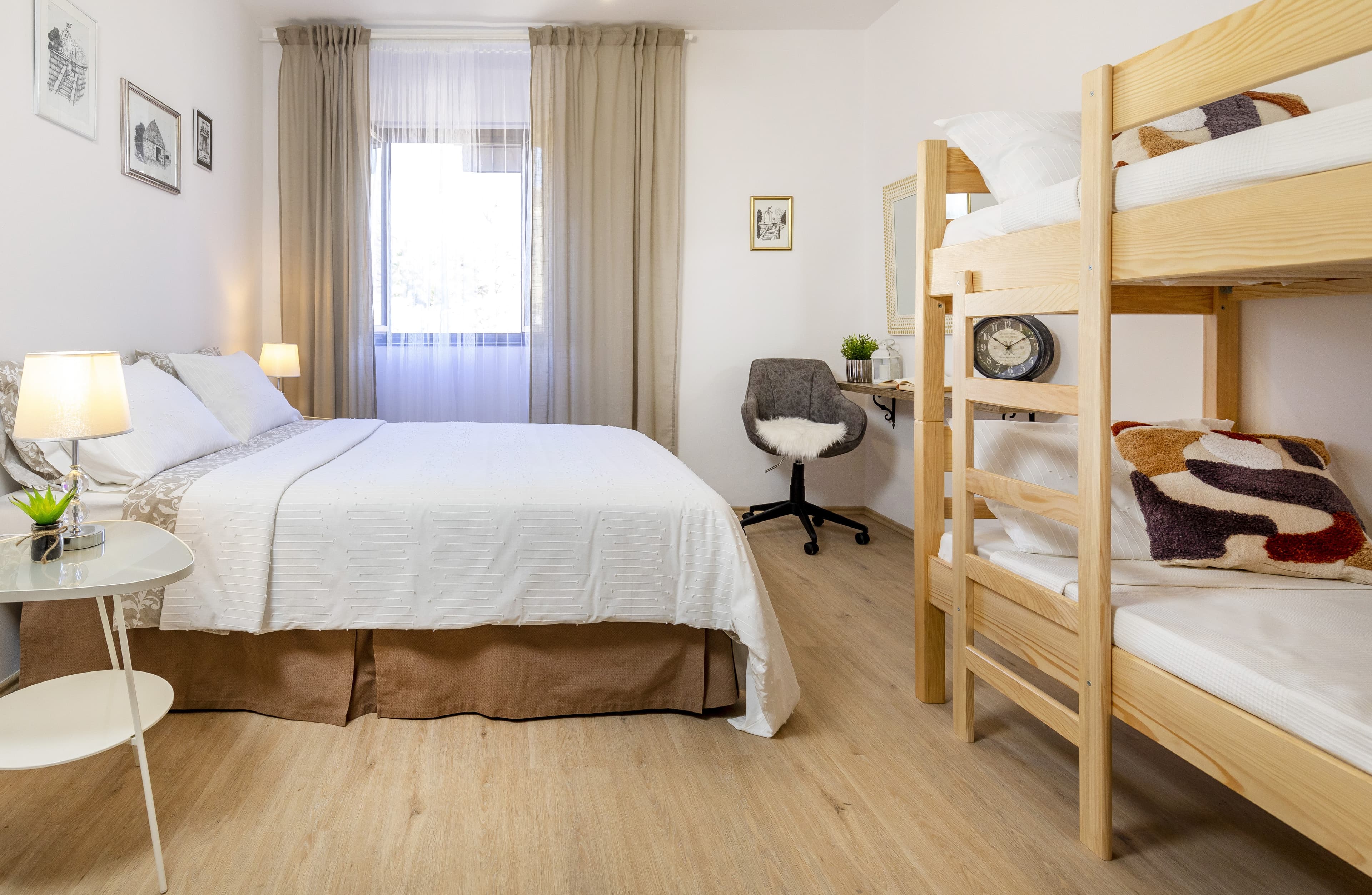 Bright bedroom featuring a white bed, wooden bunk beds, and a small desk area.